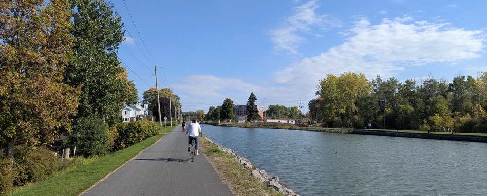01Support image_Lieu-historique-national-du-Canal-de-Chambly-credit Bich-Anh Nguyen | Sentier Transcanadien person biking along waterfront trail on a sunny day