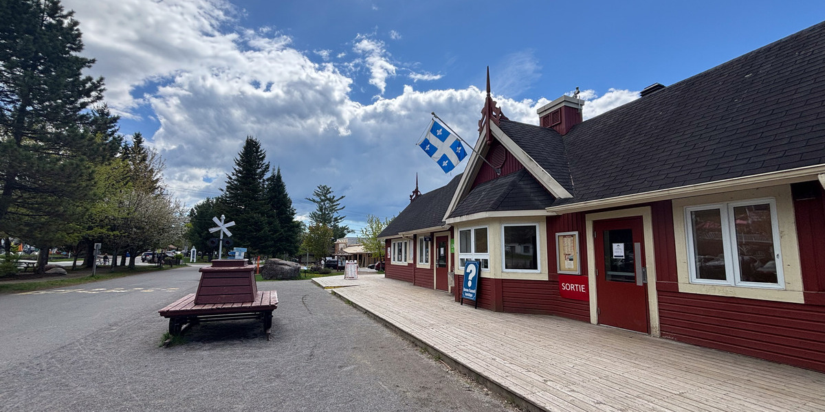 00Feature image_Ptit Train du Nord_credit Amy Schwartz | Sentier Transcanadien large house and quebec flag on a partly cloudy day