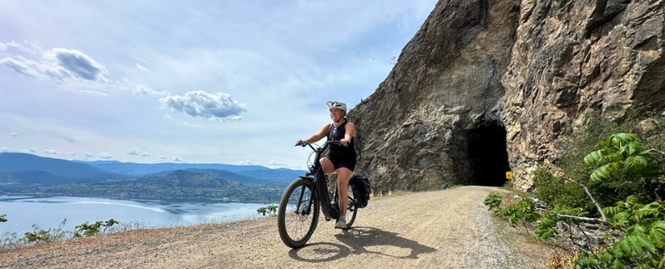cyclist in front of a large tunnel trail with sea and clouds in background