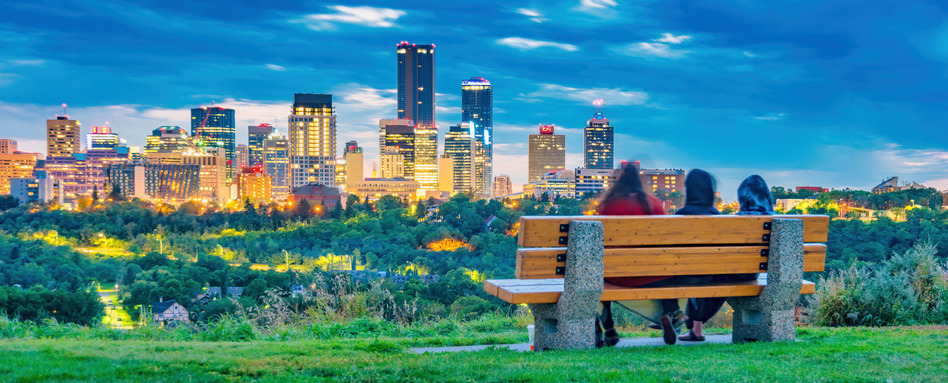 skyline view of two people sitting on a bench at dusk