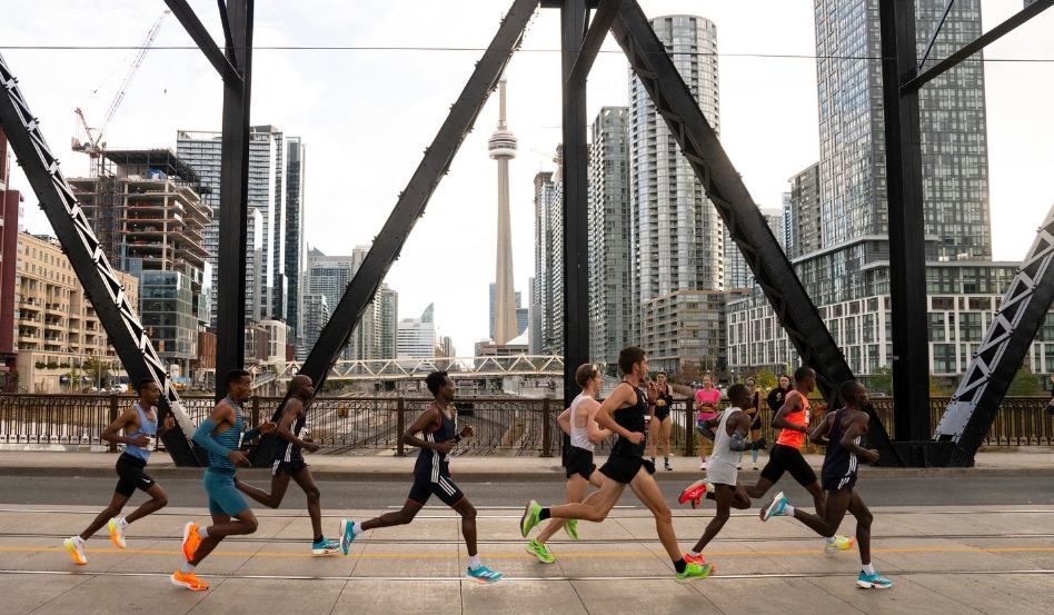 01Support image_Jen Cerullo profile_credit Canada Running Series | Sentier Transcanadien people running as a group on a bridge with toronto skyline behind