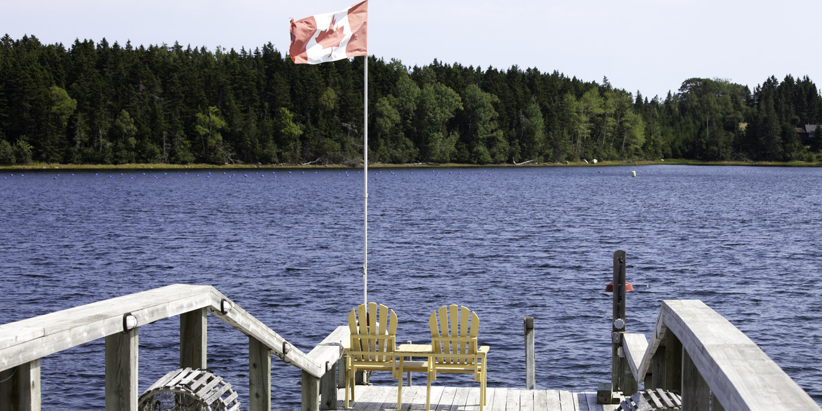 sunny dockside with camp chairs and canadian flag overlooking a lake
