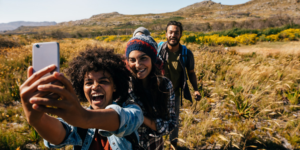 three people in a field taking a joyful selfie