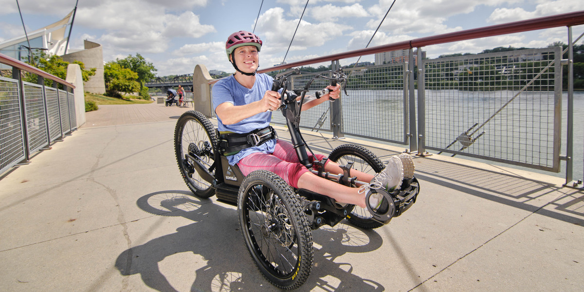 woman in wheelchair smiling on a paved over water trail
