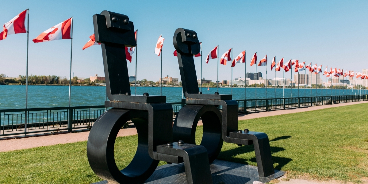 00Feature image_ON_TWEPI article_Windsor waterfroont_credit Tourism Windsor Essex Pelee Island | Sentier Transcanadien statues waterfront with canadian flags behind