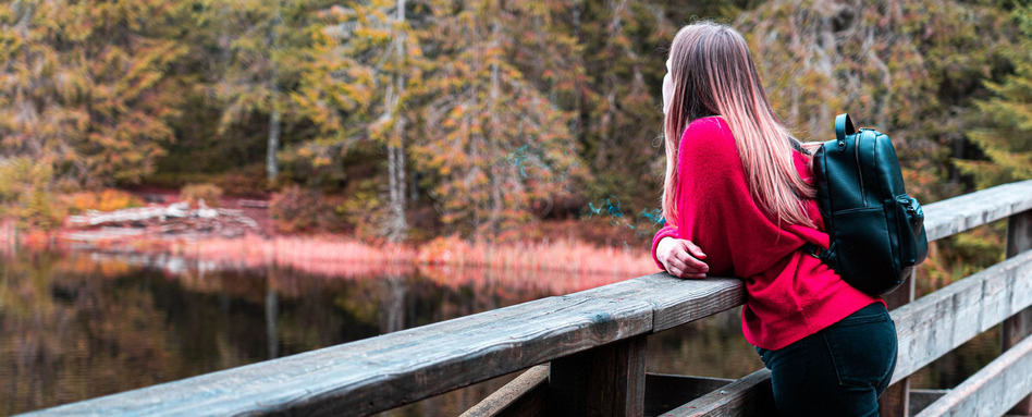 woman standing on a bridge overlooking a lake and trees