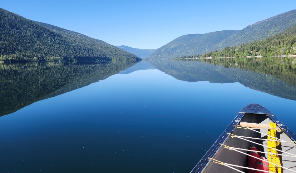 canoe on large open water with mountains on a sunny day