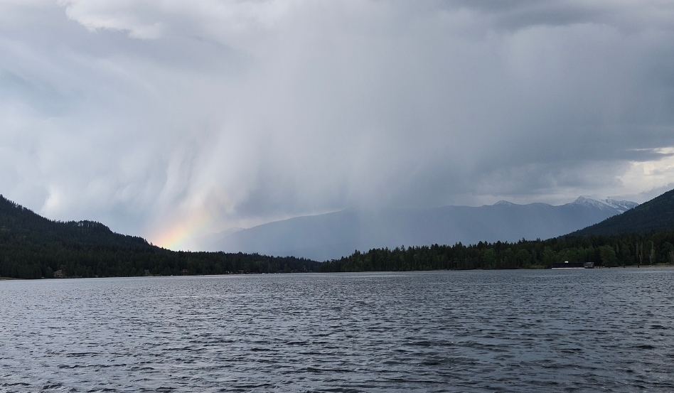 rainbow after a storm overlooking water and trees