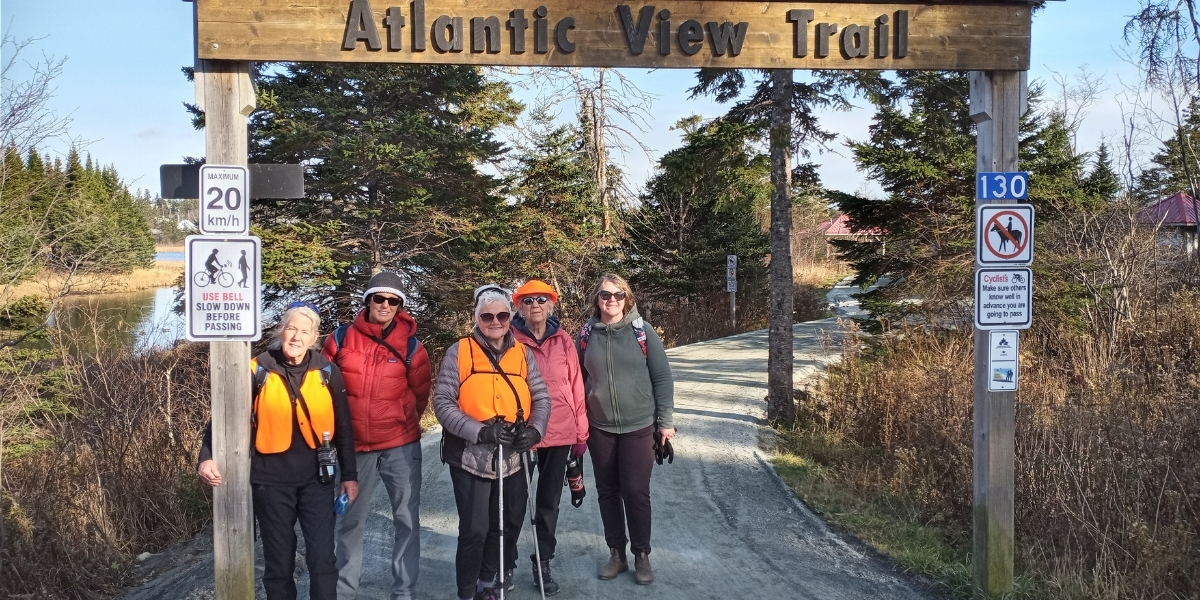 A group of hikers standing under an Atlantic View Trail sigh