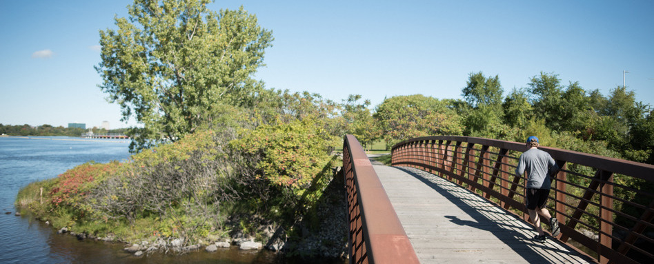man jogging on a bridge over water on a sunny day