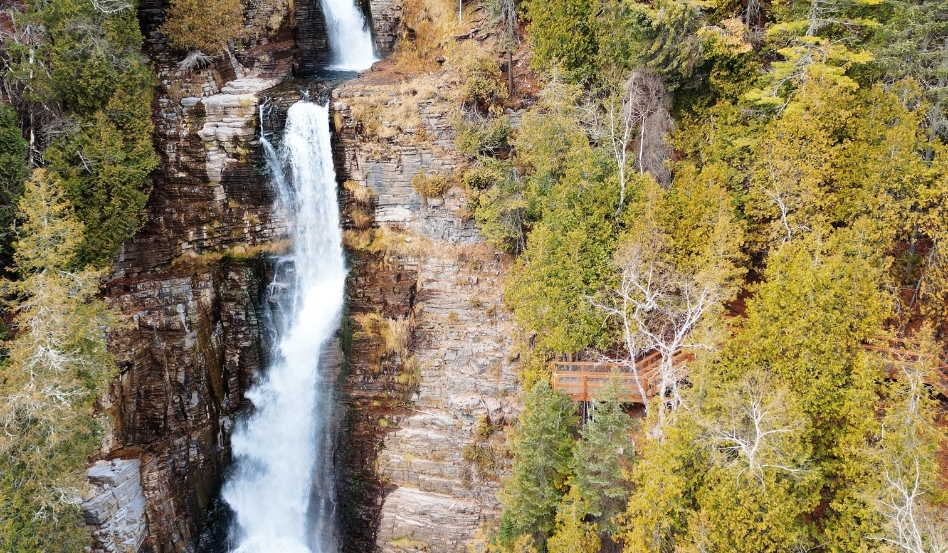 waterfall coming down the side of a cliff with surrounding greenery
