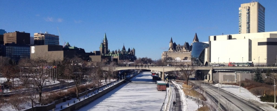 long frozen canal on a sunny day with city scape behind